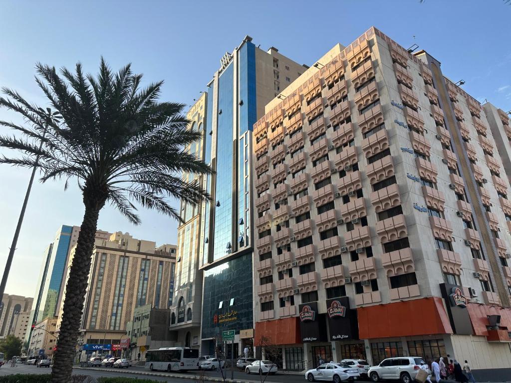 a palm tree in front of a tall building at فندق كنان العزيزية Kinan Al Azizia Hotel Makkah in Makkah