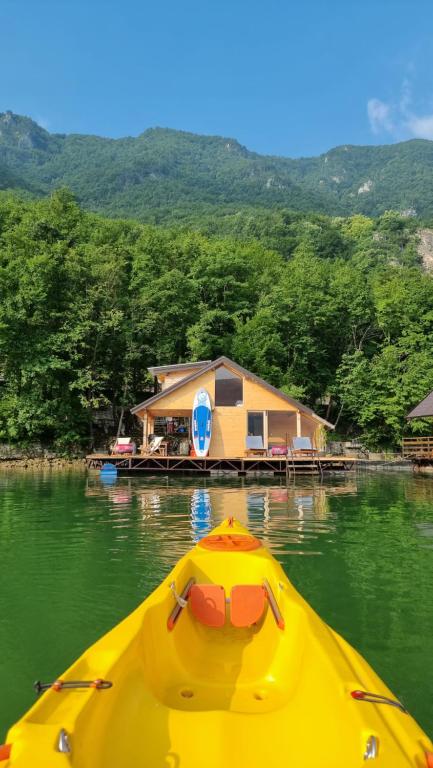 a yellow boat in the water in front of a house at Lake house Perucac in Bajina Bašta