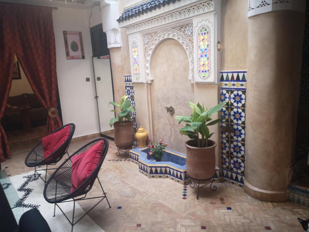Zimmer mit 2 Stühlen und einem Bogen mit Pflanzen in der Unterkunft Riad El Badii in Marrakesch