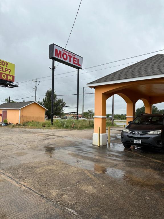 a motel with a car parked in a parking lot at Roadside Inn in Floresville