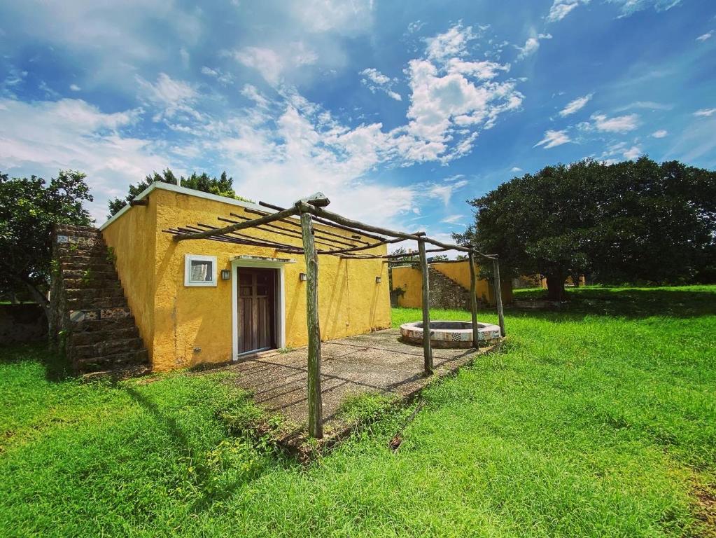 uma pequena casa amarela num campo com uma cerca em Villa en Hacienda noox Kankabal em Cholul