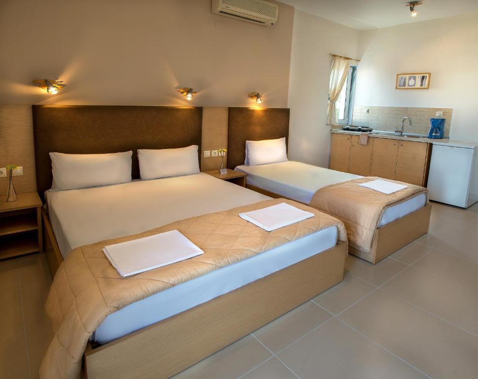 two beds in a hotel room with a kitchen at Nepheli Apartments and Studios in Paralia Katerinis