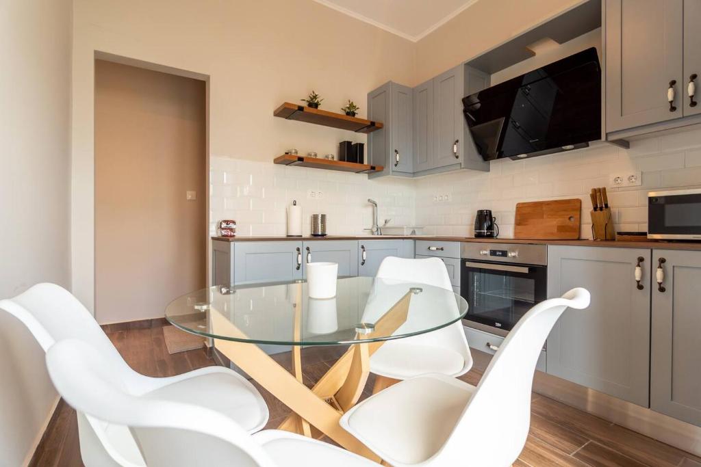 uma cozinha com uma mesa de vidro e cadeiras brancas em Theros Apartment em Palaiochora
