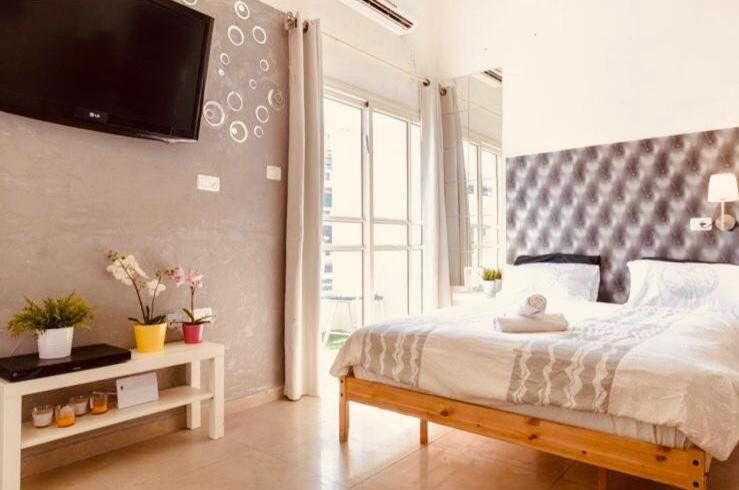 ein Schlafzimmer mit einem Bett und einem TV an der Wand in der Unterkunft דיזנגוף סנטר חניה פרטית מרפסת שמש in Tel Aviv