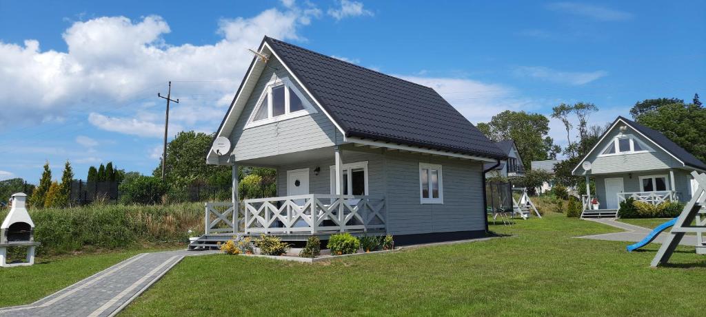 una pequeña casa en un patio con parque infantil en Szary domek nad jeziorem, en Kołczewo