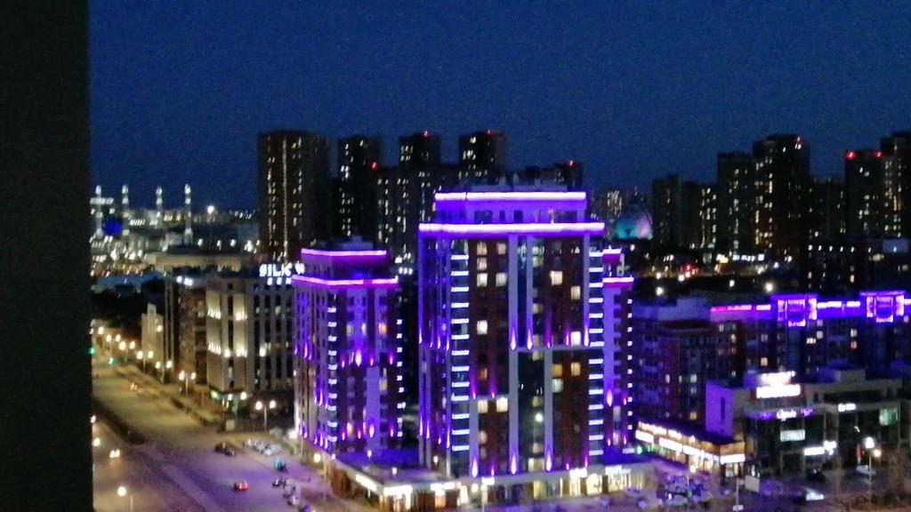 een nachtzicht op een stad met paarse lichten bij 1 комн квартира Тауельсиздик 34-2 18 этаж ЖК Silk Way in Promyshlennyy