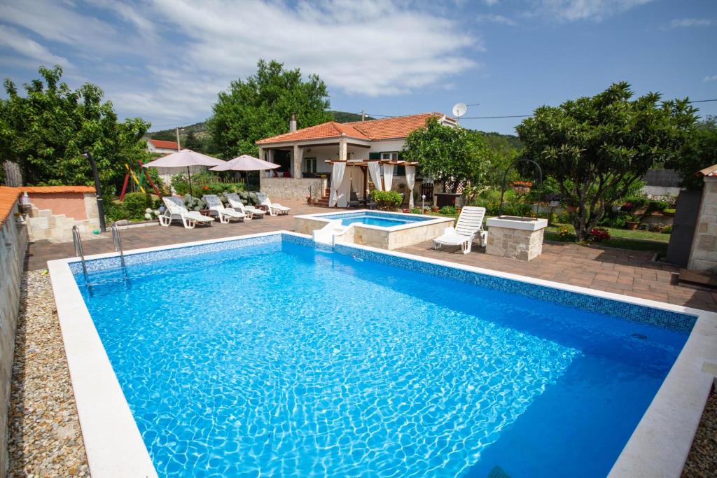 - une piscine d'eau bleue en face d'une maison dans l'établissement Villa Kata, à Vrpolje