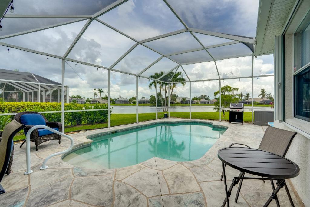 einen Pool in einem Gewächshaus mit einem Tisch und Stühlen in der Unterkunft Sunny Fort Myers Home with Heated Pool! in Fort Myers