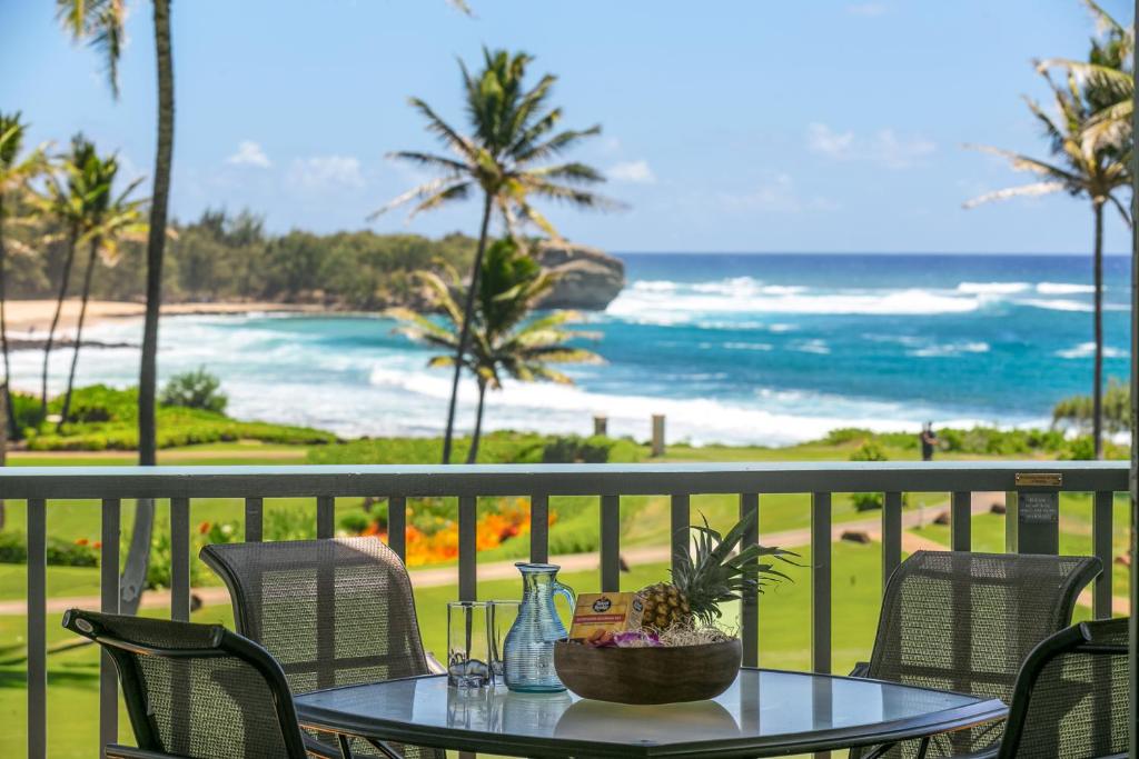 a table on a balcony with a view of the ocean at Prime Oceanfront Condo near Shipwreck Beach - Alekona Kauai in Koloa