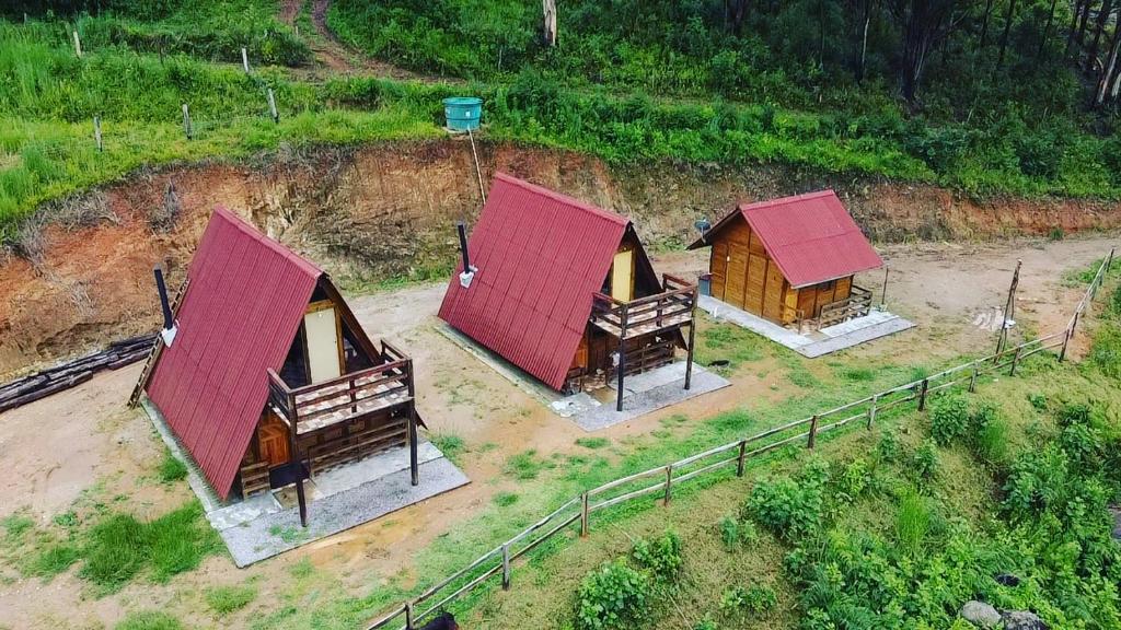 MunhozにあるPousada Pedra da Mata chalés na montanhaの野原にある赤い屋根の小さな小屋3軒