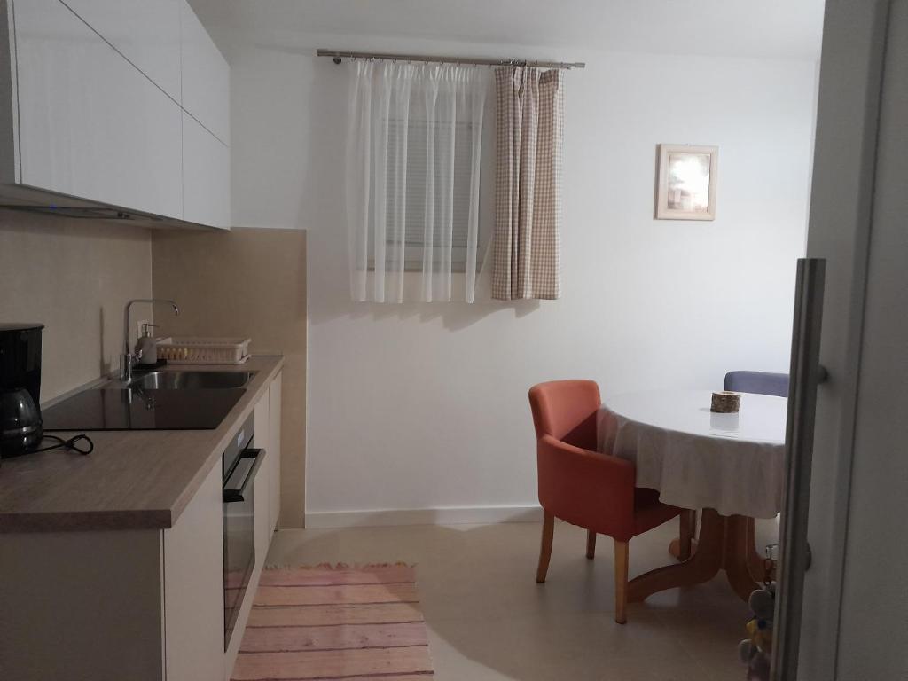uma cozinha com uma mesa e uma cadeira vermelha em Apartman 1 em Omišalj