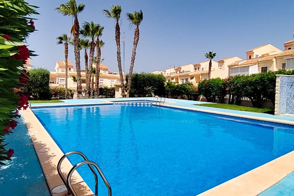 uma grande piscina azul com palmeiras e casas em Villa del Sol em Gran Alacant