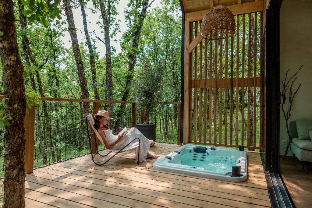 a woman sitting in a chair on a deck with a hot tub at Wabi sabi lodge&spa in Turenne