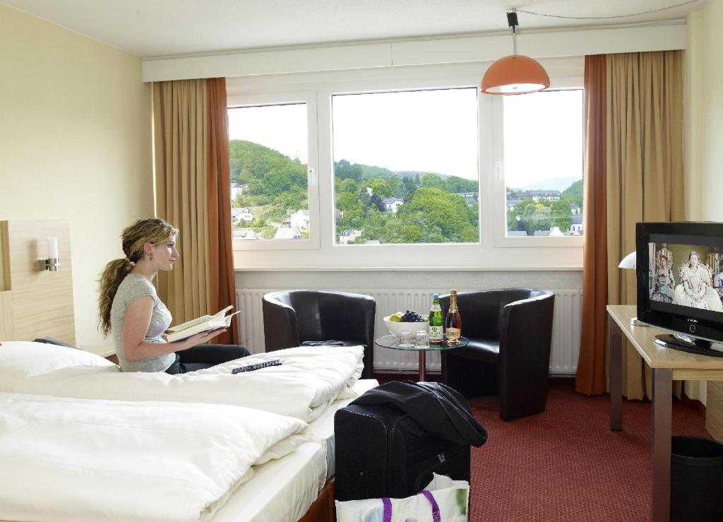 een vrouw op een bed in een hotelkamer bij Opal Hotel in Idar-Oberstein