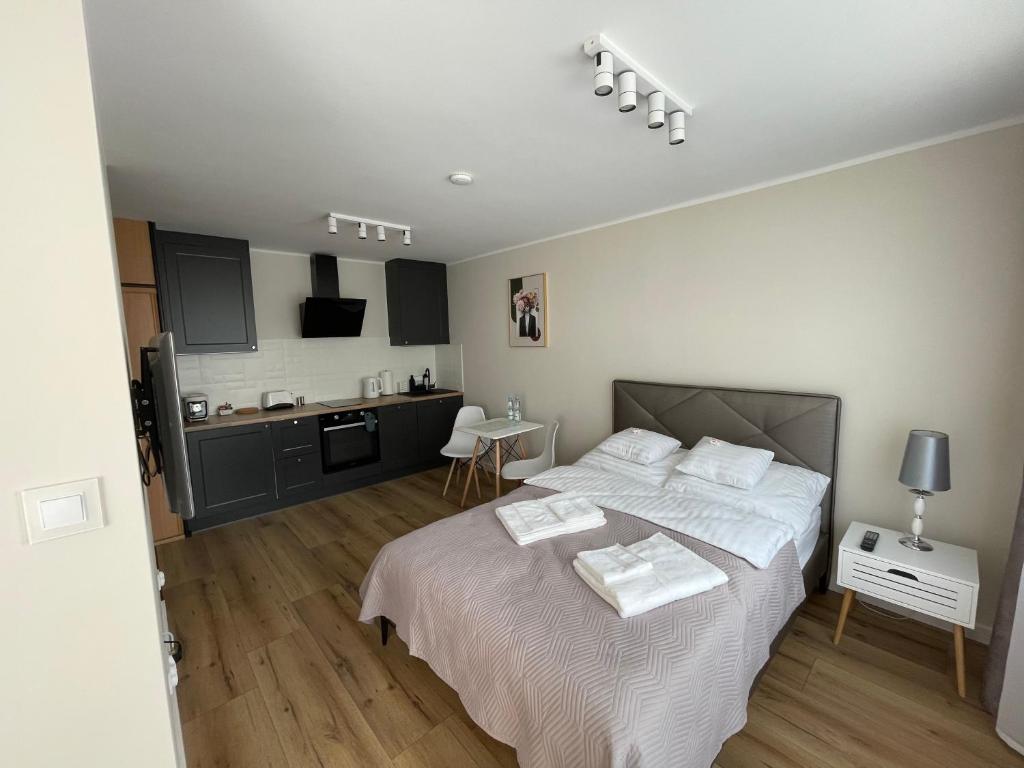 a bedroom with a large bed and a kitchen at Apartament Radiowa Premium in Olsztyn