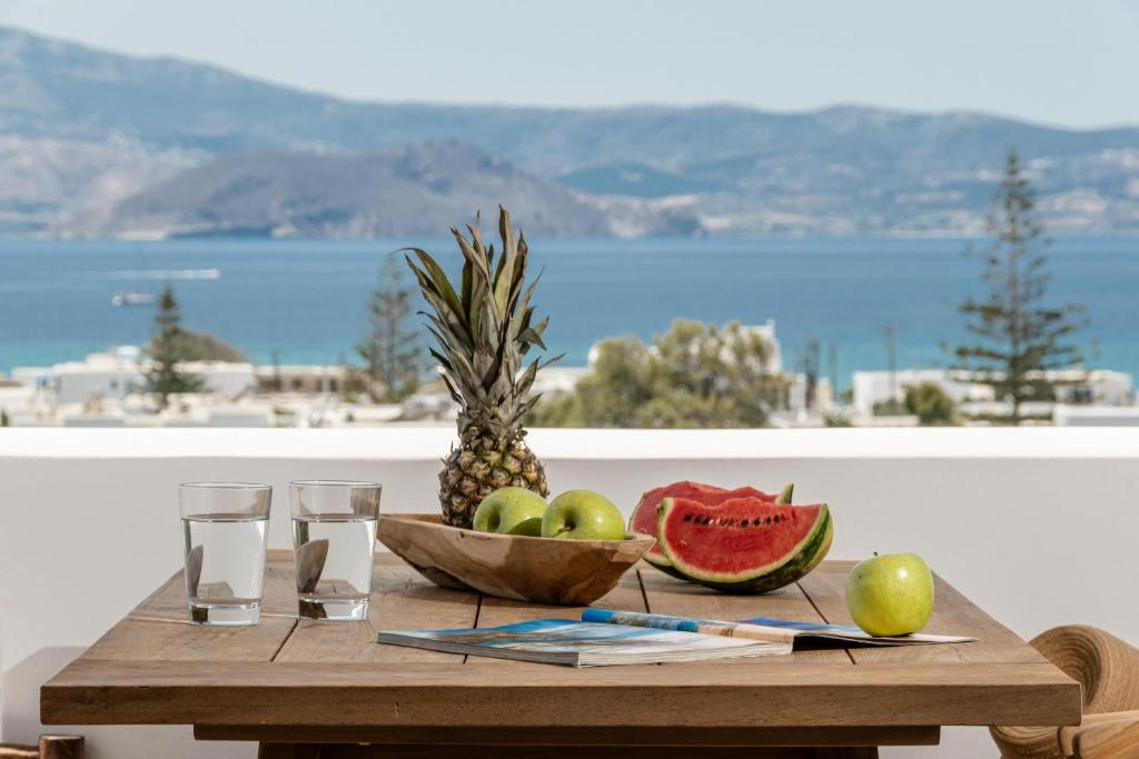 un tavolo in legno con un cesto di frutta e bicchieri di Vita Residence ad Agia Anna Naxos