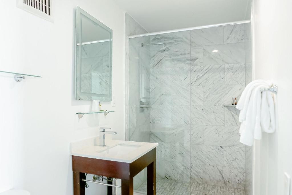 uma casa de banho branca com um lavatório e um chuveiro em Capri Laguna on the Beach - A Boutique Hotel em Laguna Beach