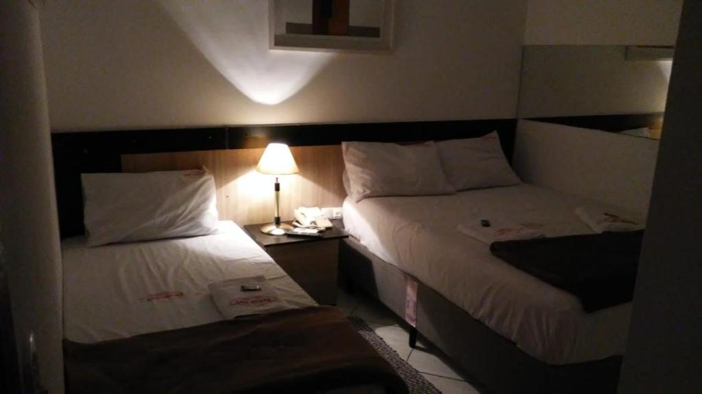 une chambre d'hôtel avec deux lits et une lampe dans l'établissement Hotel Las Vegas Guarulhos, à Guarulhos