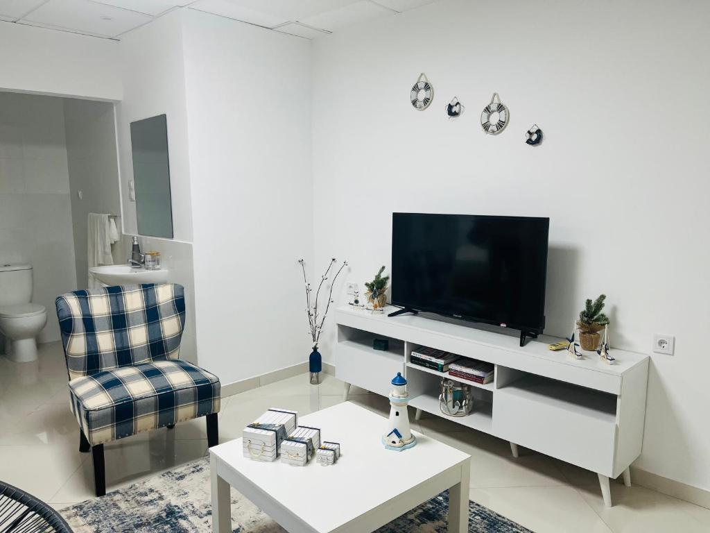 a living room with a tv and a chair and a table at Techas City Center Luxurious Suites & Rooms in Praia