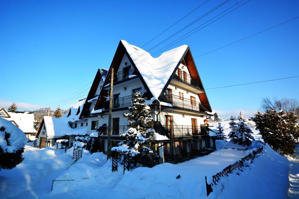 uma casa grande com um telhado coberto de neve em Apartamenty Willa Anna em Poronin