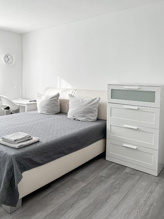 a white bedroom with a bed and a dresser at 3 Zimmer Wohnung bei Frankfurt / Neu renoviert in Egelsbach