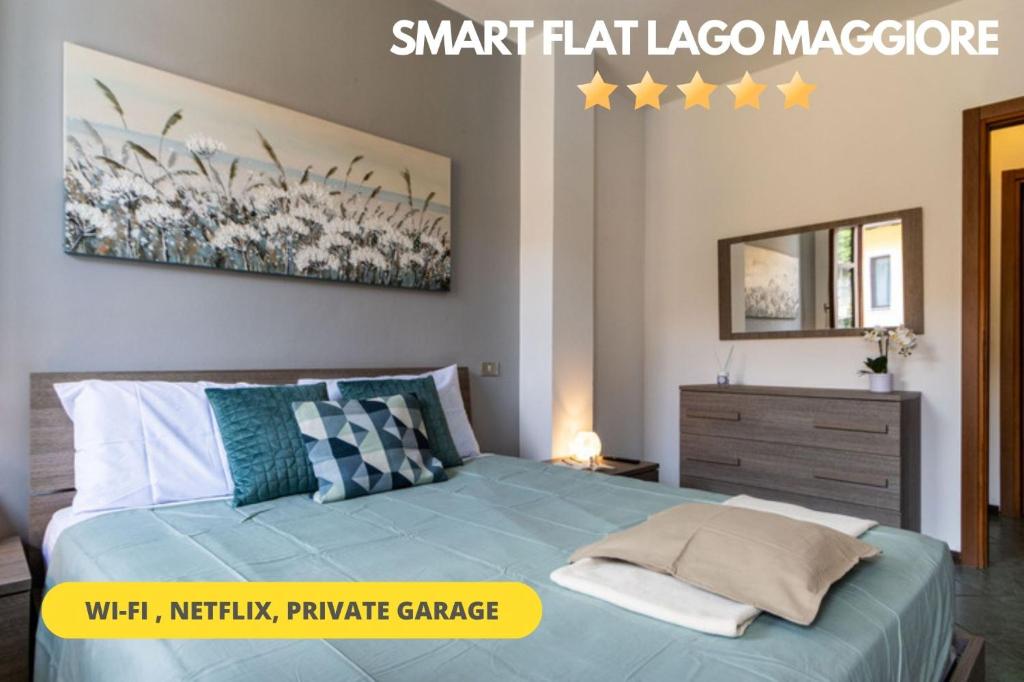 Un dormitorio con una cama azul con una pintura en la pared en [SMART FLAT] Private Garage, Wi-Fi, Netflix en Castelletto sopra Ticino