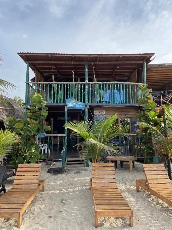 ein Gebäude am Strand mit Stühlen davor in der Unterkunft the mompe beach hostal in La Poza