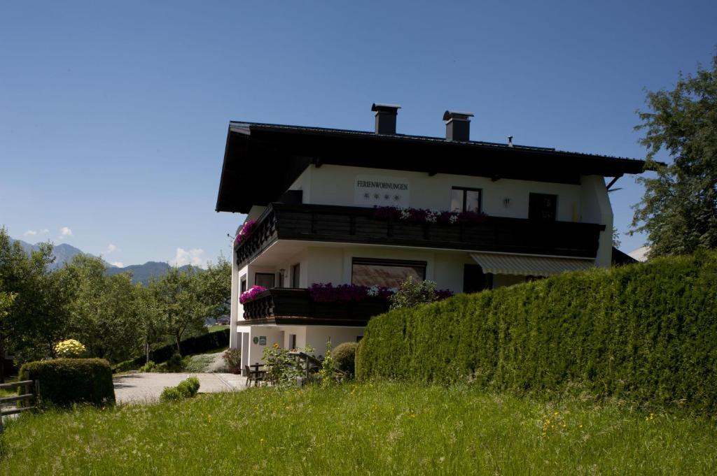 ein Haus auf einem Hügel mit Blumen auf dem Balkon in der Unterkunft Ferienwohnung Ronacher in Abtenau