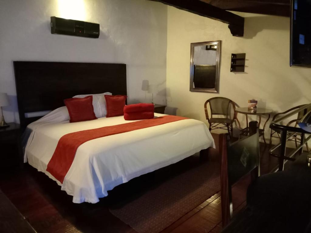 Hotel Boutique Casabella في كواتيبيك: غرفة نوم بسرير ومخدات حمراء وطاولة