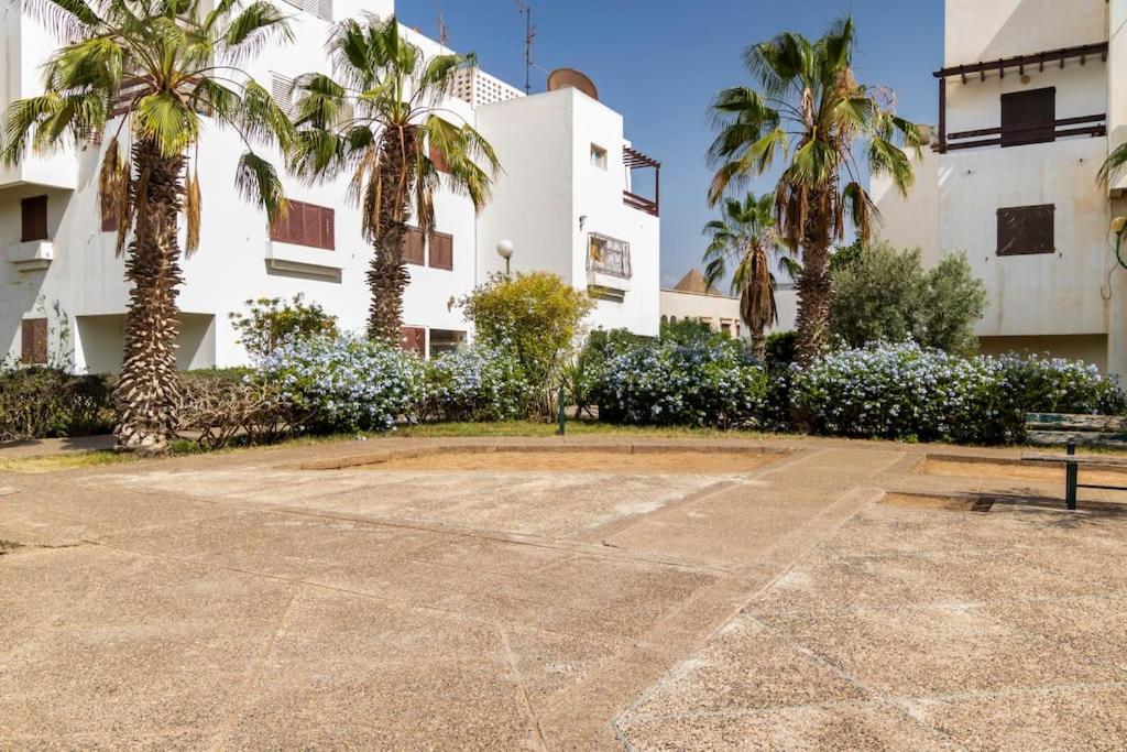 um edifício com palmeiras em frente em Appartement chaleureux et calme, Parking, Jardin em Agadir