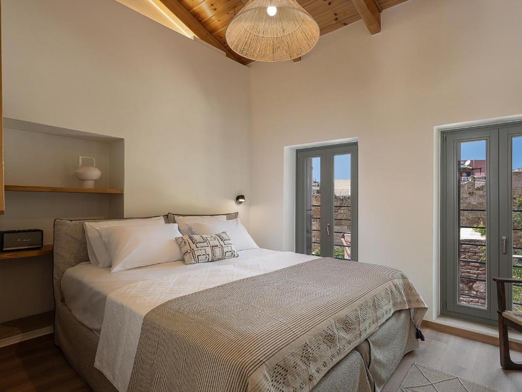 1 dormitorio con 1 cama grande y 2 ventanas en Theros Home en La Canea