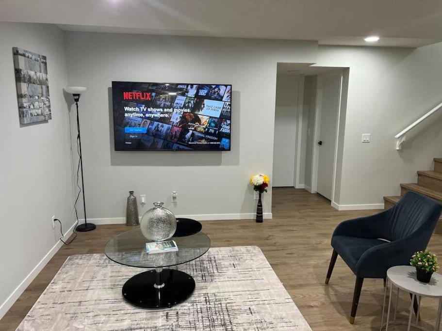 a living room with a table and a tv on the wall at 2-bedroom basement apartment in Calgary