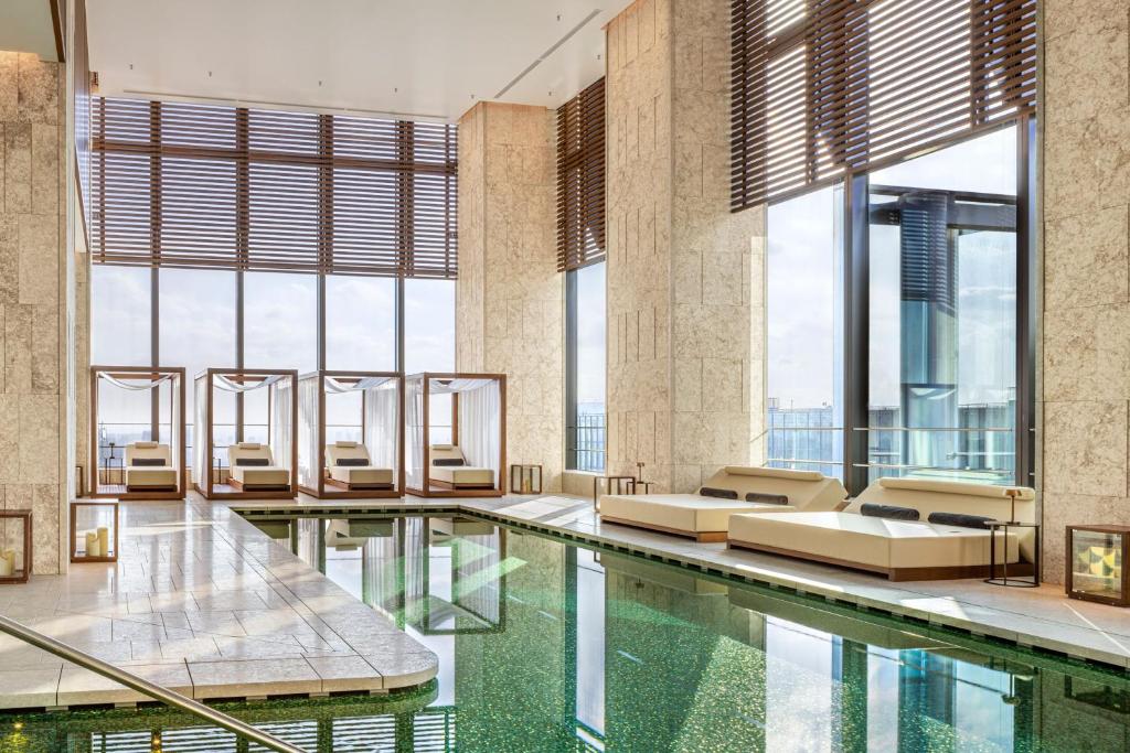 東京的住宿－Bulgari Hotel Tokyo，一座带窗户的建筑中,设有一座带沙发和椅子的游泳池