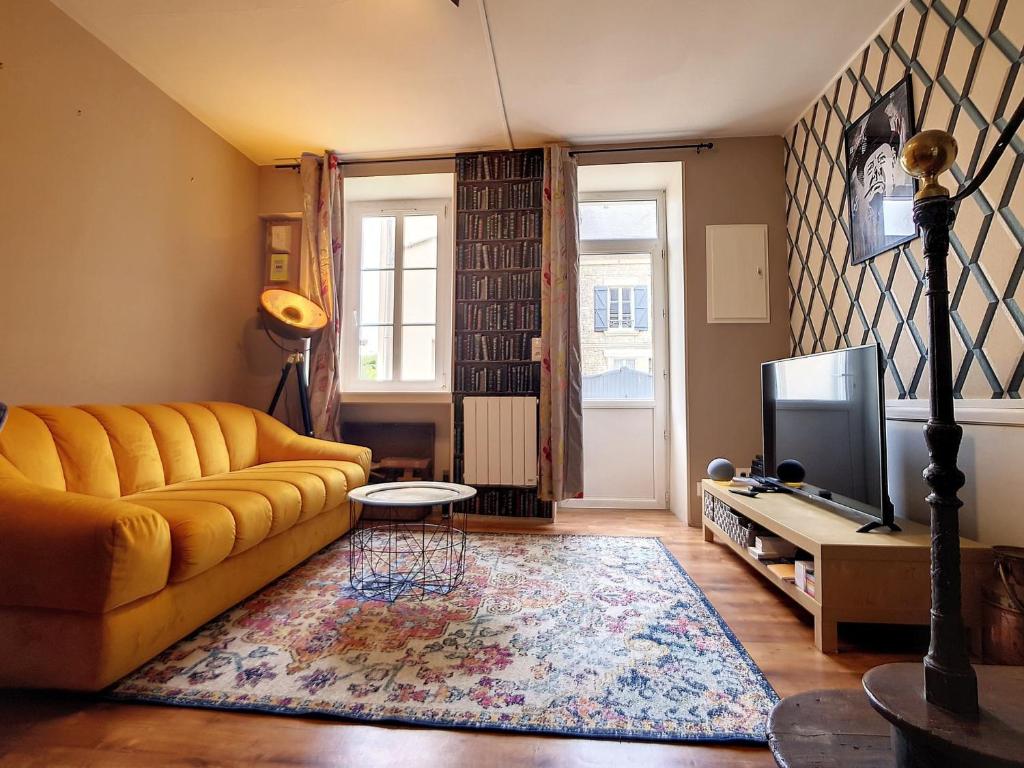 ein Wohnzimmer mit einem gelben Sofa und einem TV in der Unterkunft Maison Port-en-Bessin-Huppain, 3 pièces, 4 personnes - FR-1-746-9 in Port-en-Bessin-Huppain