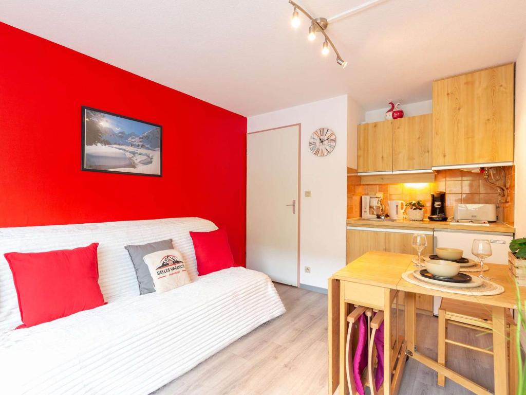 a bedroom with a red wall with a bed and a table at Appartement Saint-Lary-Soulan, 2 pièces, 4 personnes - FR-1-296-472 in Saint-Lary-Soulan