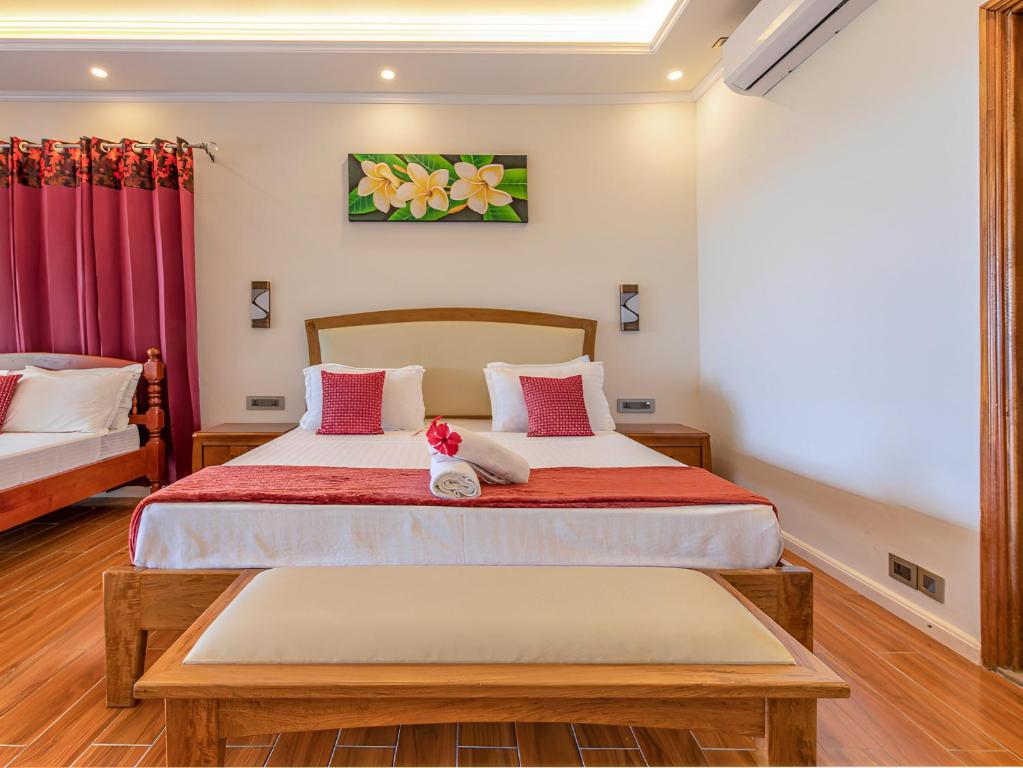 Anse aux Pins的住宿－美森迪阿岩旅館，一间卧室配有一张带红色和白色枕头的大床