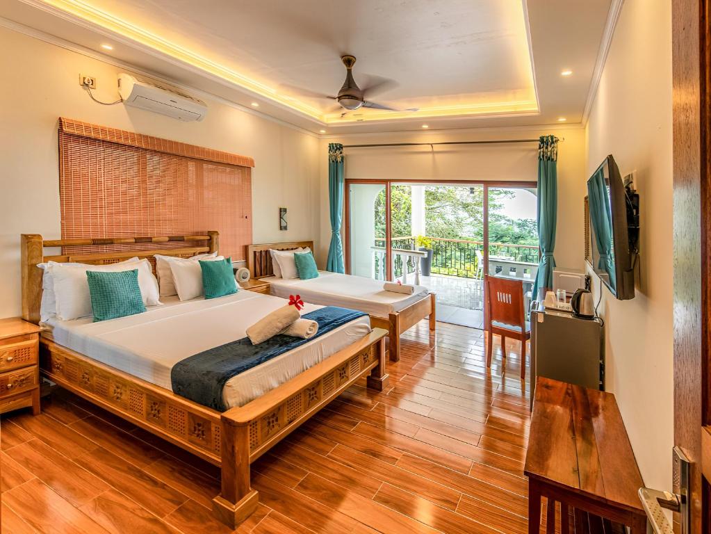 a bedroom with two beds and a large window at Maison D'Aaryan in Anse aux Pins