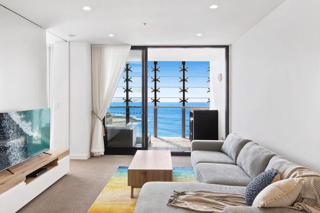 a living room with a couch and a large tv at Exceptional Beach views - Luxury apartment in Newcastle