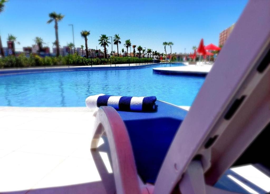 a pool with a lounge chair next to a swimming pool at Prime chalet in Golf Porto Marina resort new Alamein in El Alamein