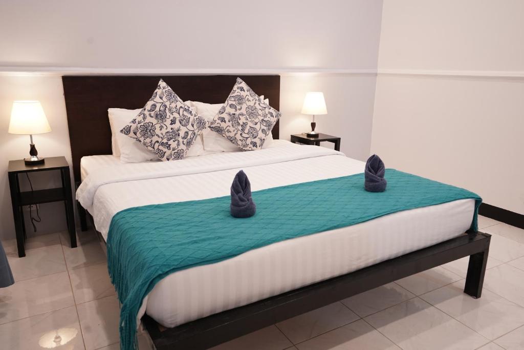 a bedroom with a large bed with a green blanket at Birdcage Boutique in Phnom Penh