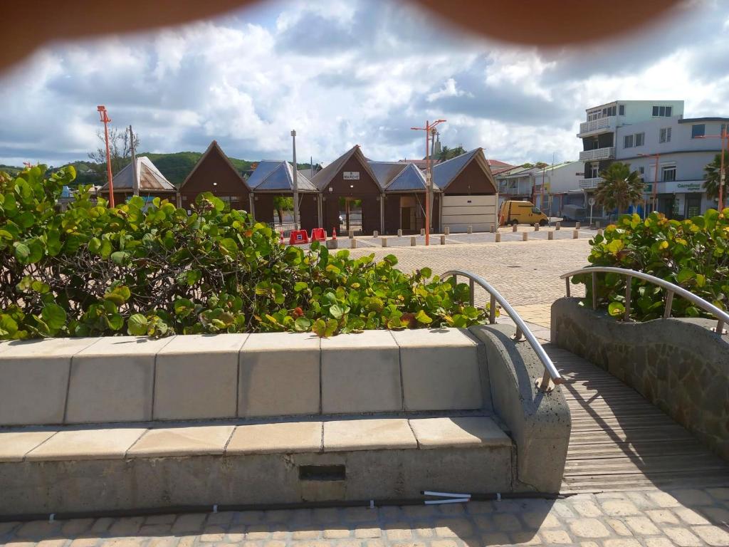 a stone bench with bushes and houses in the background at Appartement d&#39;une chambre avec balcon et wifi a Le Vauclin a 3 km de la plage in Le Vauclin