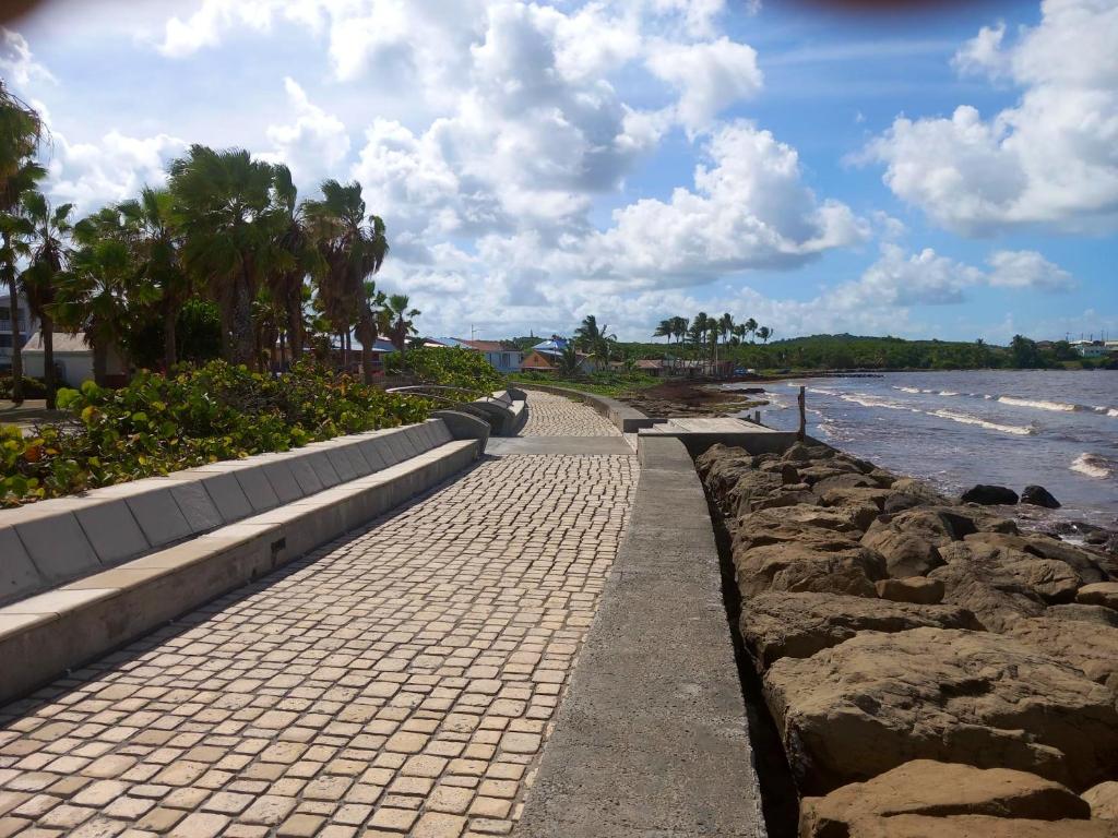 a brick walkway next to a beach with rocks at Appartement d&#39;une chambre avec balcon et wifi a Le Vauclin a 3 km de la plage in Le Vauclin