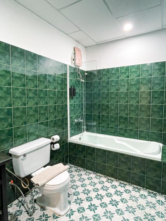 a green tiled bathroom with a toilet and a tub at Birdcage Boutique in Phnom Penh