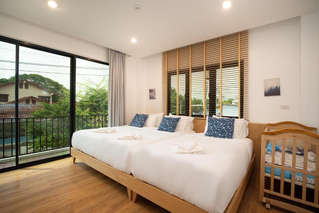 a bedroom with two beds and a large window at The Modeva Hotel in Kanchanaburi