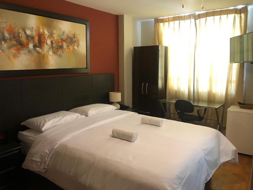 a bedroom with a large white bed with two pillows on it at Hotel Las Condes in Trujillo