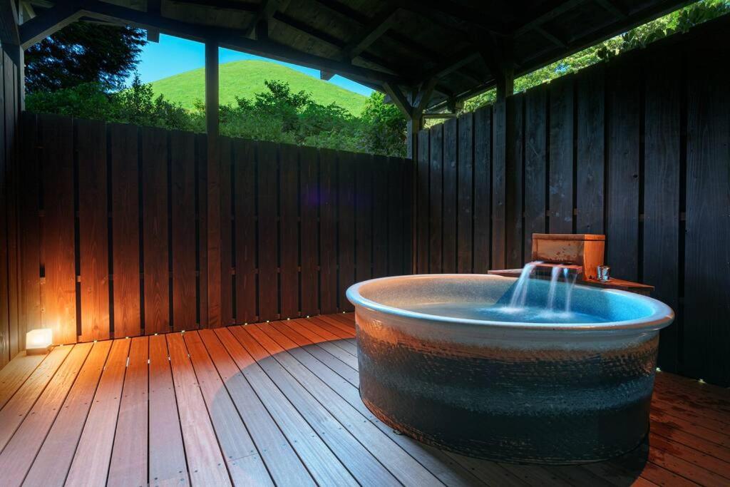 a bath tub sitting on a deck with a wooden floor at じぇーむすのおうち in Yawatano