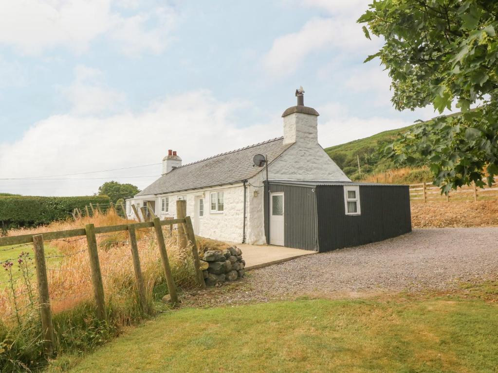 a white cottage with a black garage at Ty Hen in Pwllheli