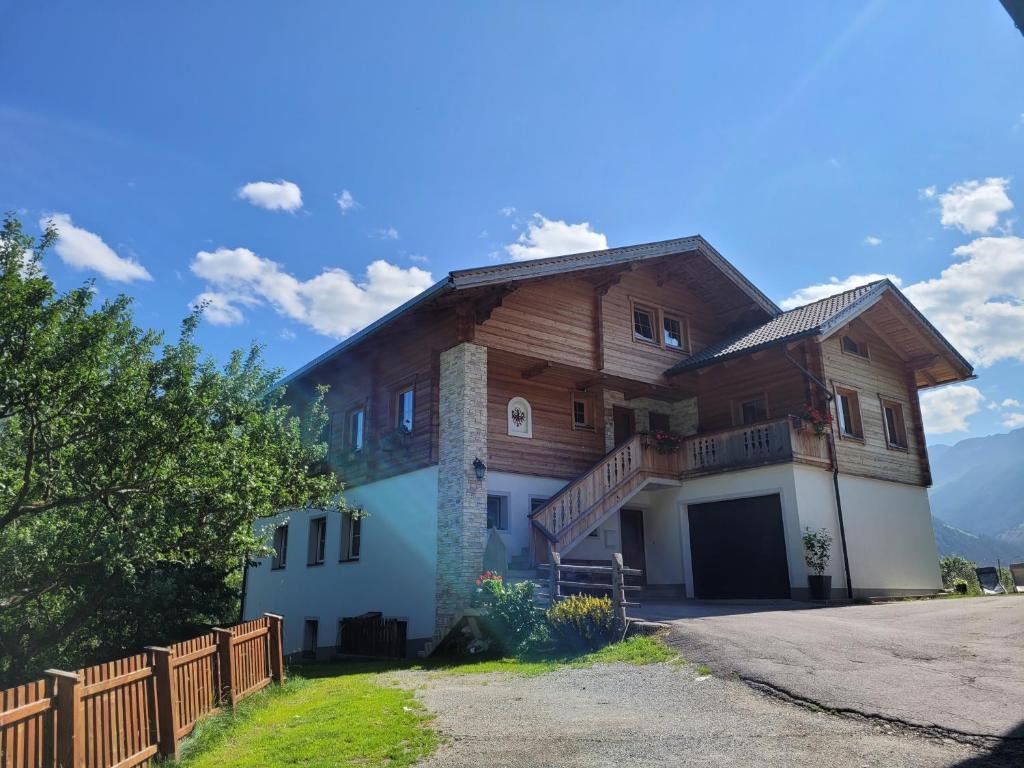a large wooden house with a fence in front of it at Gästehaus Bergwald - Pötscherjahringerhof in Virgen