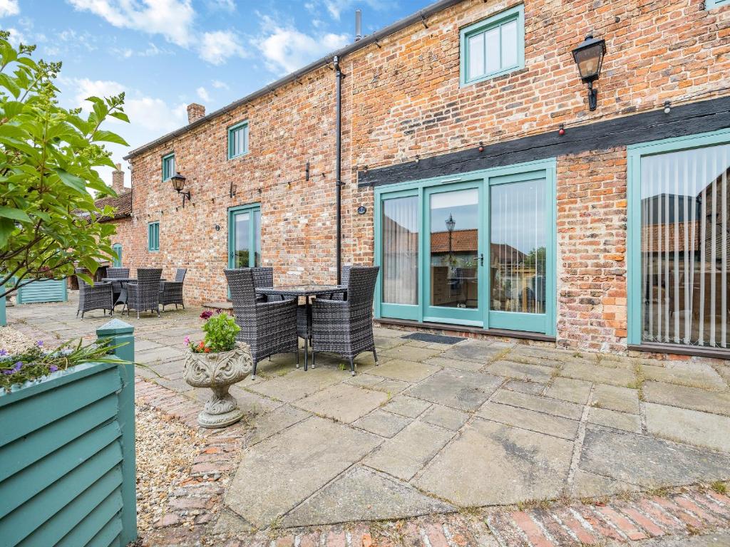 een patio met een tafel en stoelen voor een bakstenen gebouw bij The Hayloft - Uk44519 in Tetney