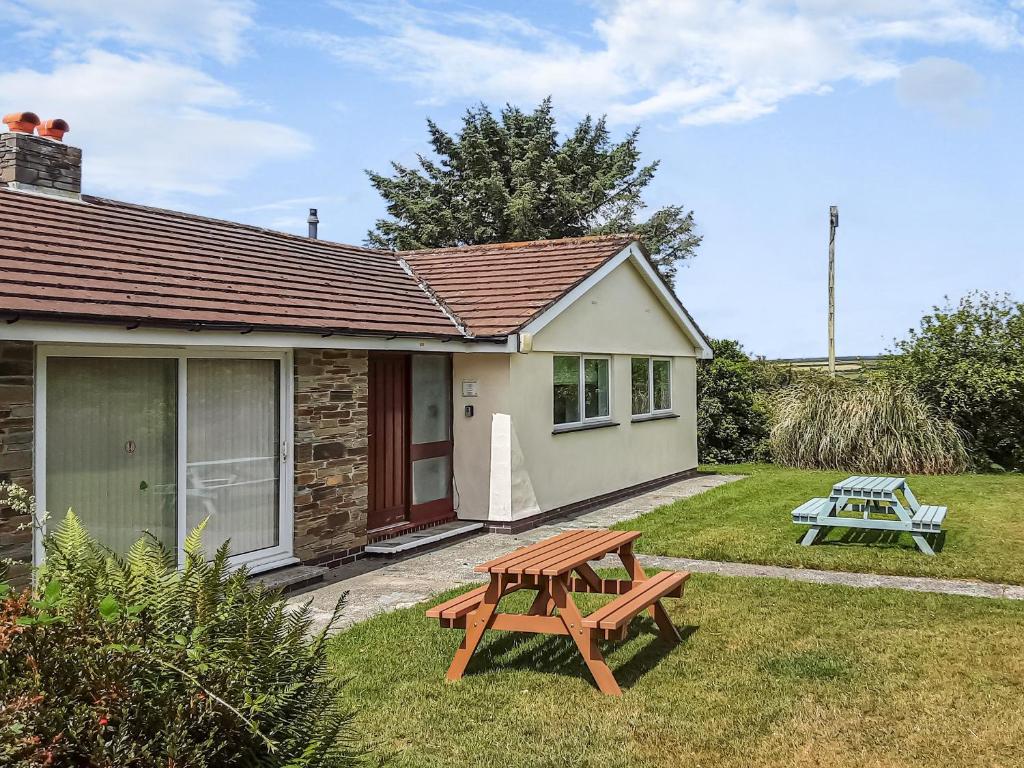 a picnic table in front of a small house at Valley Truckle Bungalow in Camelford